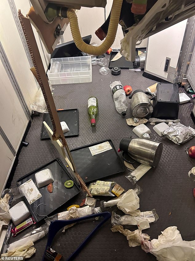 Wine bottles, kettles and food trays are seen scattered across the floor of the cabin