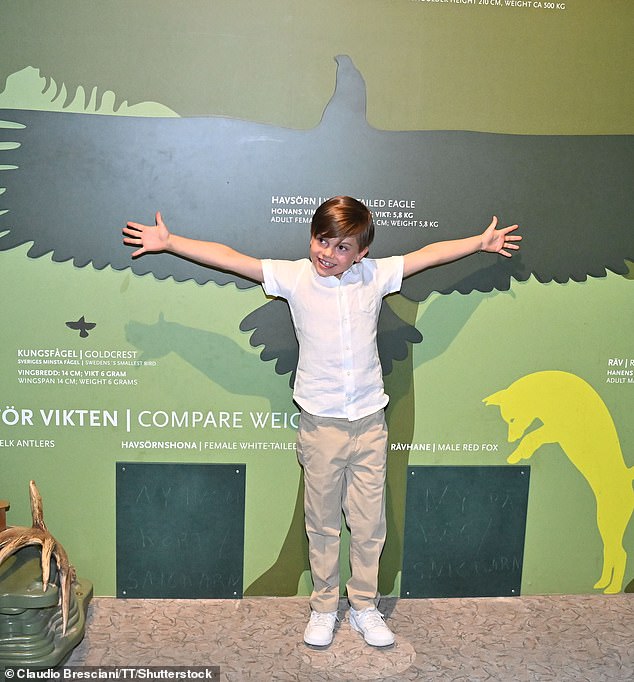Her youngest child appeared delighted as he took in the display, playfully posing by a poster with an eagle