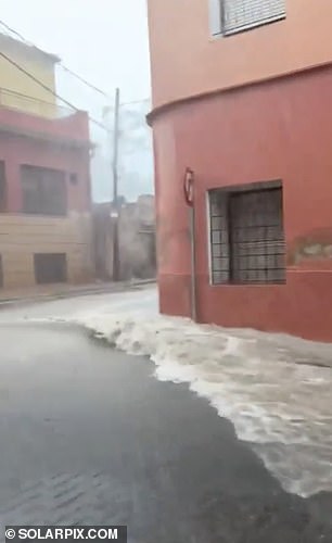 Water is seen gushing down the streets of Murcia on Monday as the south-eastern region of Spain was hit by torrential rain