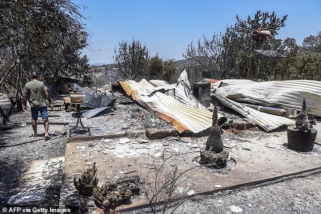 A man walks past debris of a building destroyed in a wildfire in the village of Choulou in western Cyprus on June 12, 2024.