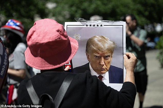 A Trump supporter holding a sign of the ex-president's mugshot outside the Manhattan criminal court on the day he was convicted on 34 counts of falsifying business records