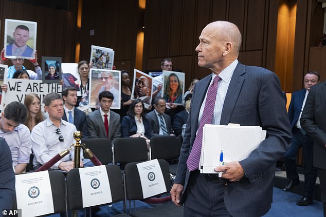 Boeing CEO Dave Calhoun looks at protesters and families of victims as he arrives