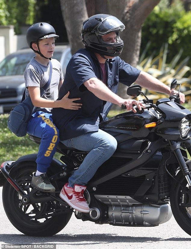 Affleck kept it casual in a navy blue button-up over a maroon T-shirt with denim jeans and Nike sneakers