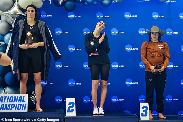 Lia Thomas accepts the winning trophy for the 500 Freestyle finals as second place finisher Emma Weyant and third place finisher Erica Sullivan watch in March of 2022