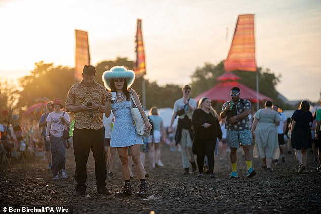 People walk through the market and shopping area at the Glastonbury Festival yesterday