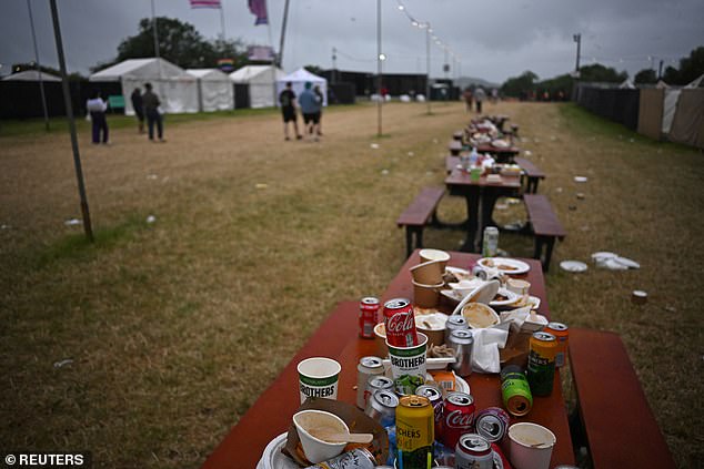 People walk near rubbish discarded by revellers during the Glastonbury Festival today