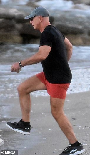 Bezos wore a black T-shirt, paired with red shorts, and gray and black Hoka sneakers