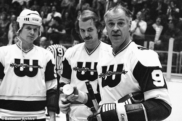 A little fatherly advice as hockey great Gordie Howe accepts a gold puck from his sons and teammates Mark and Marty Howe (c) in recognition of his 1,000th goal