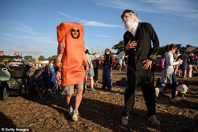 Revellers dressed as a fish finger and Captain Birdseye dance to music on day three of the festival