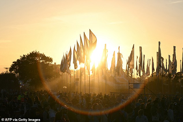 The sun sets behind festivalgoers on the third day of the Glastonbury festival at Worthy Farm