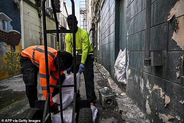 Workers put bags of sand at the back door of a shop in preparation for the arrival of Hurricane Beryl in Bridgetown, Barbados on June 30, 2024