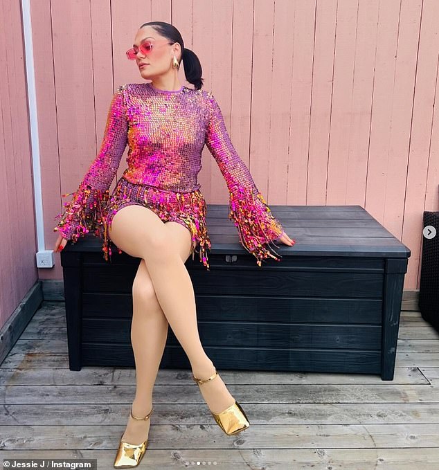 The musician struck a serious pose as she paired her jaw-dropping garment with quirky gold heels and 90s-inspired pink-tinted sunglasses