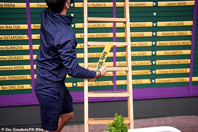 A member of ground staff removes the name of Andy Murray from a order of play board at Wimbledon today