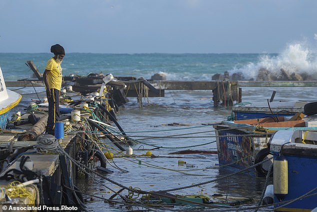 A fisherman looks out at vessels damaged by Hurricane Beryl at the Bridgetown Fisheries in Barbados, Monday, July 1, 2024