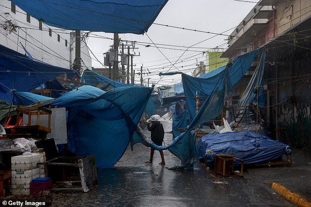 A person makes their way through the wind and rain from Hurricane Beryl Wednesday, as towering waves and high-speed winds hit Jamaica