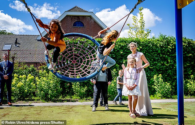 With her hair brushed back into a chignon, the Dutch monarch looked on as children played on the equipment in the playground