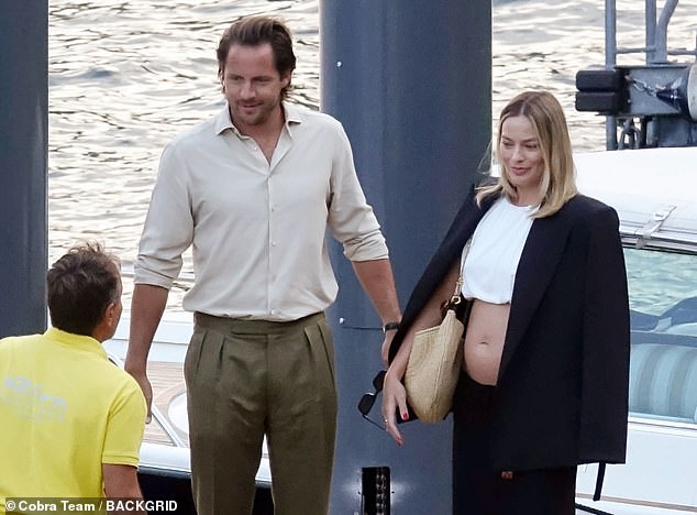 Margot displayed her blossoming baby bump while boarding a boat in Lake Como in Italy with her husband last week