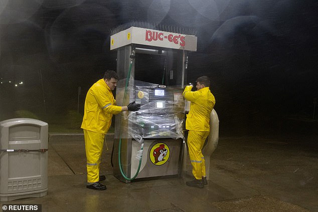 Workers wrap plastic around a fuel pump to protect it from wind and rain due to Hurricane Beryl at Buc-ee's, in Freeport, Texas early Monday morning