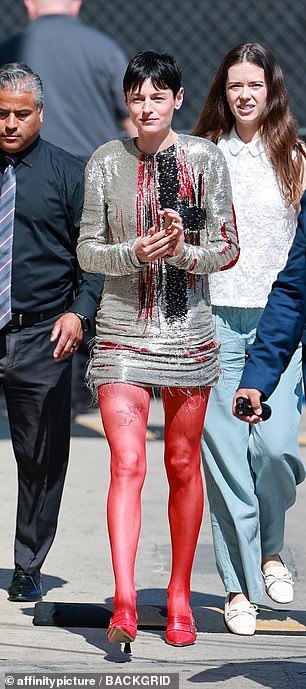 The actor, 28, showed off their quirky style in a silver embellished mini dress, teamed with sheer red tights and pointed toe heels