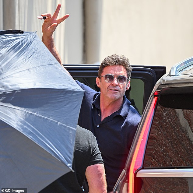 Hugh arrived on the set in good spirits,  flashing the waiting crowds a peace sign as he emerged from his vehicle in a black polo shirt with dark shades to match