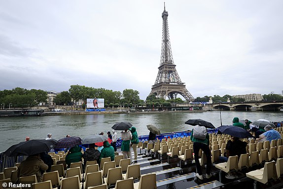 Paris 2024 Olympics - Opening Ceremony - Paris, France - July 26, 2024. Spectators hold umbrellas in the rain in front of the Eiffel Tower ahead of the Opening Ceremony REUTERS/Louisa Gouliamaki