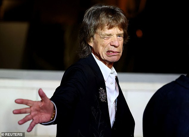 Mick pulled funny faces and stretched out his hand theatrically as he graced the event's dark green carpet