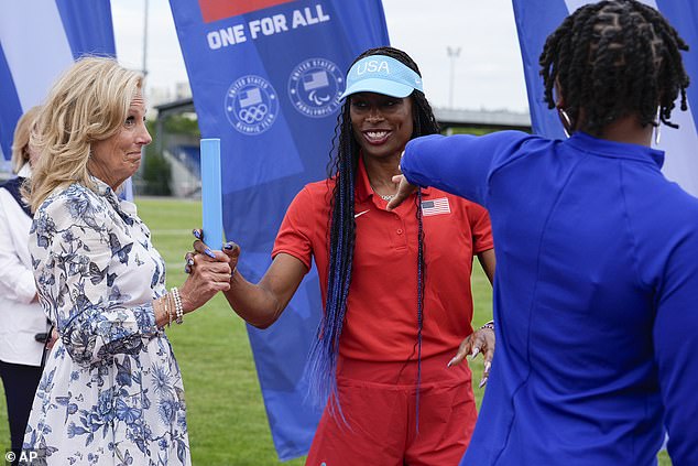 Jill Biden, left, learns the proper technique to pass a baton from head women's relay coach Mechelle Freeman, center