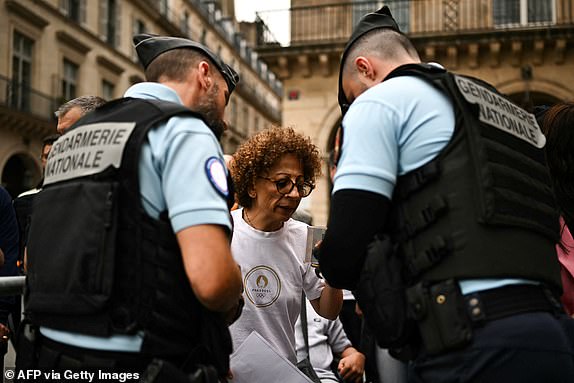 TOPSHOT - French gendarmes control members of the public as they access one of the spot near the Louvre Museum to attend the opening ceremony of the Paris 2024 Olympic Games in Paris on July 26, 2024. (Photo by Ben STANSALL / AFP) (Photo by BEN STANSALL/AFP via Getty Images)