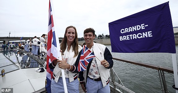 Britain's flagbearers Helen Glover, left and Thomas Daley pose during the opening ceremony for the 2024 Summer Olympics in Paris, France, Friday, July 26, 2024. (Naomi Baker/Pool Photo via AP)