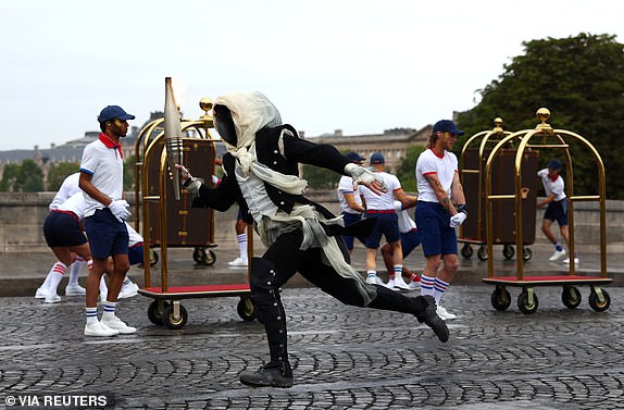 Paris 2024 Olympics - Opening Ceremony - Paris, France - July 26, 2024. A torchbearer runs past Pont Neuf during the opening ceremony of the Olympic Games Paris 2024.  Maddie Meyer/Pool via REUTERS