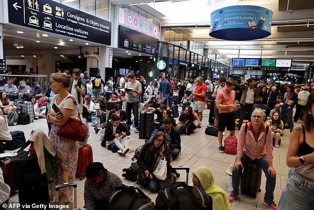 Passengers wait for their train departures at the Gare Montparnasse train station in Paris on July 26, 2024 as France's high-speed rail network was hit by malicious acts disrupting the transport system