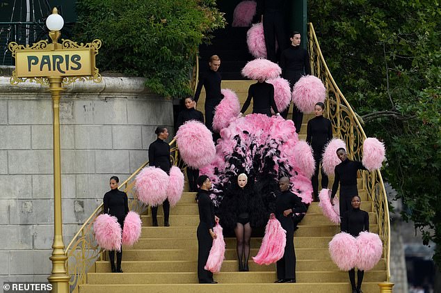 Backup performers hold fluffy pink handles in contrast to Gaga's black outfit