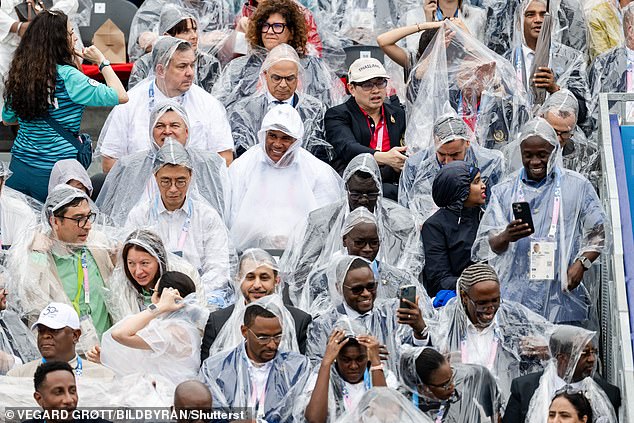 Spectators cover themselves in plastic ponchos as the ceremony gets underway