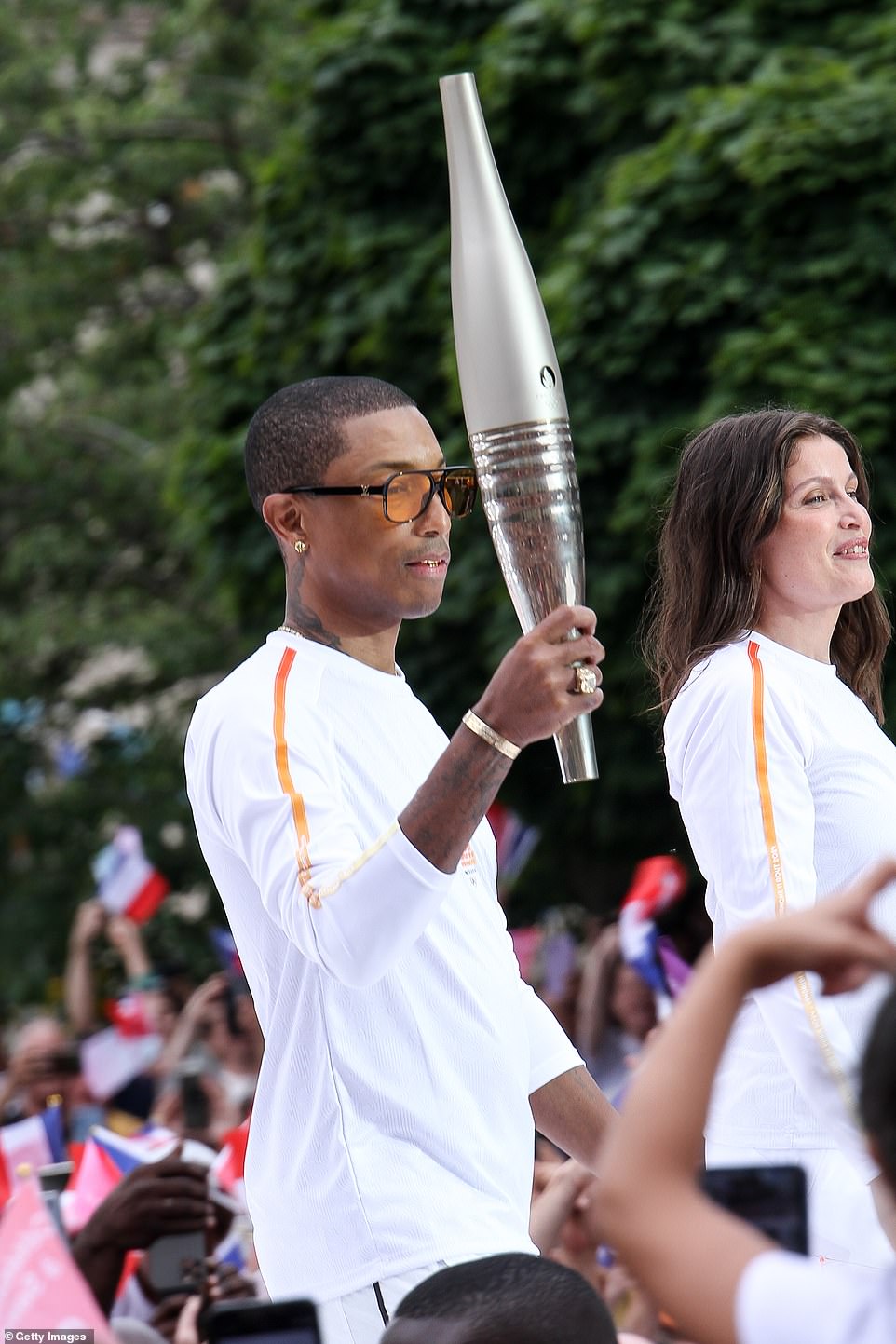 The Happy hitmaker had a look of concentration on his face as he took part in the torch relay alongside French model and actress Laetitia Casta