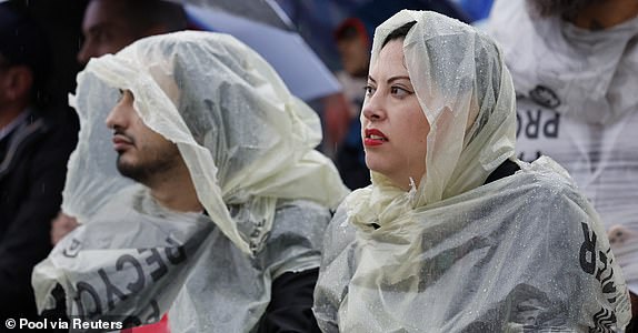 Paris 2024 Olympics - Opening Ceremony - Paris, France - July 26, 2024. Spectators cover their heads from the rain wearing recycling bags as they watch the floating parade on the river Seine during the opening ceremony Pool via REUTERS/Stefan Wermuth