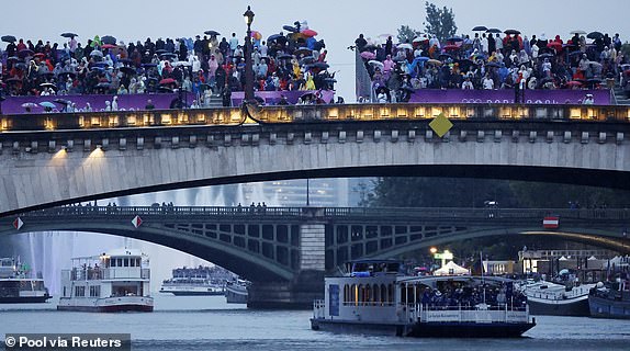 Paris 2024 Olympics - Opening Ceremony - Paris, France - July 26, 2024. Spectators are seen looking on from stands on a bridge as the floating parade passes by along the river Seine during the opening ceremony Pool via REUTERS/Clodagh Kilcoyne