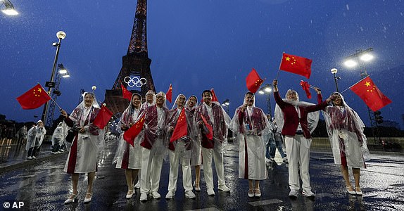 Representatives from China walk on a bridge near the Eiffel Tower during the opening ceremony of the 2024 Summer Olympics, Friday, July 26, 2024, in Paris, France. (AP Photo/Andy Wong)