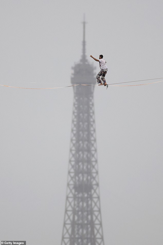 Tightrope walker Nathan Paulin performs on a high rope during the athletes' parade on the River Seine