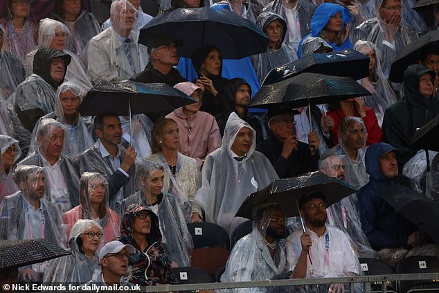 Crowds forced to wear ponchos and hold up brollies during the torrential rain