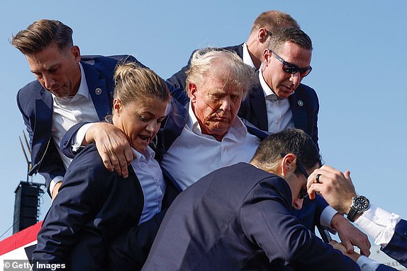 BUTLER, PENNSYLVANIA - JULY 13: Republican presidential candidate former President Donald Trump is rushed offstage by U.S. Secret Service agents after being grazed by a bullet during a rally on July 13, 2024 in Butler, Pennsylvania. Butler County district attorney Richard Goldinger said the shooter is dead after injuring former U.S. President Donald Trump, killing one audience member and injuring another in the shooting. (Photo by Anna Moneymaker/Getty Images) 13639619