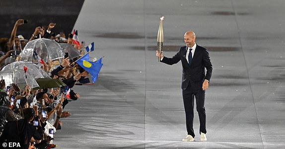 epa11498100 Zinedine Zidane carries the Olympic flame torch at Trocadero during the Opening Ceremony of the Paris 2024 Olympic Games, in Paris, France, 26 July 2024.  EPA/Joel Marklund / POOL