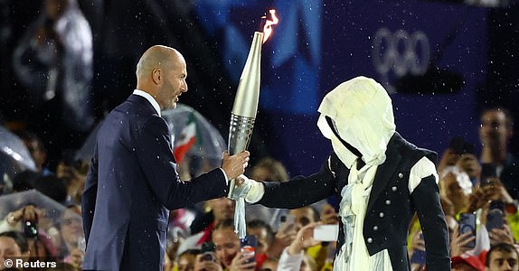 Paris 2024 Olympics - Opening Ceremony - Paris, France - July 26, 2024.  Zinedine Zidane takes the torch during the opening ceremony REUTERS/Kai Pfaffenbach