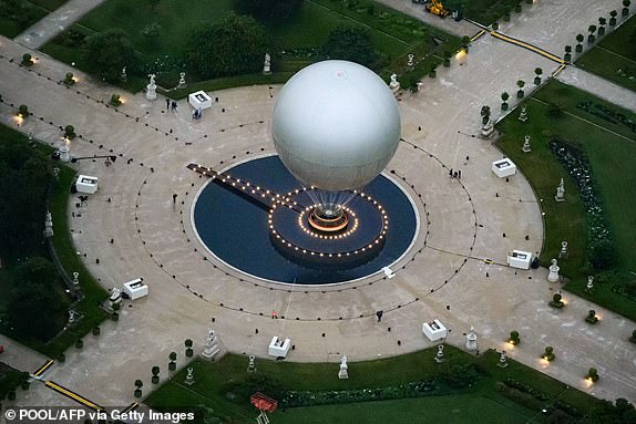 TOPSHOT - A photograph taken from an helicopter on July 26, 2024 shows an aerial view of a ballon attached to the cauldron (unseen) in the Tuileries garden during the opening ceremony of the Paris 2024 Olympic Games in Paris. (Photo by Lionel BONAVENTURE / POOL / AFP) (Photo by LIONEL BONAVENTURE/POOL/AFP via Getty Images)