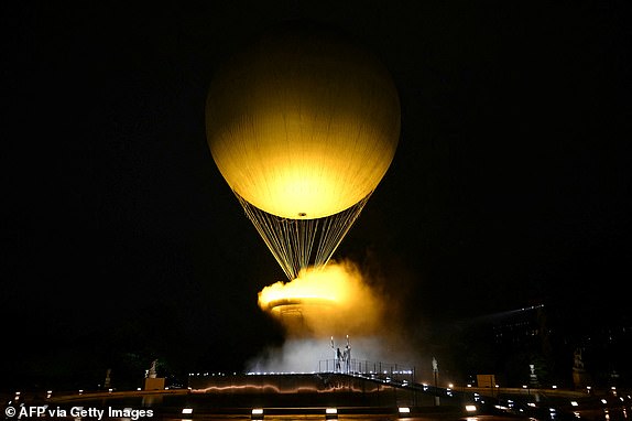 TOPSHOT - The cauldron, with the Olympic flame lit, lifts off while attached to a balloon as the torchbearers French former sprinter Marie-Jose Perec and French judoka Teddy Riner stand in front during the opening ceremony of the Paris 2024 Olympic Games at the Jardin des Tuileries (Tuileries Garden) in Paris on July 26, 2024. (Photo by MOHD RASFAN / AFP) (Photo by MOHD RASFAN/AFP via Getty Images)