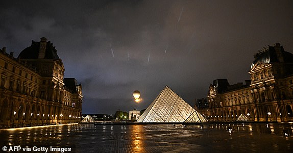 TOPSHOT - The cauldron, with the Olympic flame lit, lifts off while attached to a balloon, during the opening ceremony of the Paris 2024 Olympic Games in Paris on July 26, 2024, as the Louvre Pyramid is seen next to it. (Photo by JUNG Yeon-je / AFP) (Photo by JUNG YEON-JE/AFP via Getty Images)