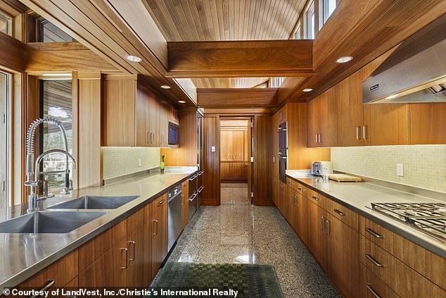 The gourmet galley kitchen (pictured) has a large gas stove, a stainless steel range hood, thick wooden beams above, granite floors and more modern stainless steel appliances