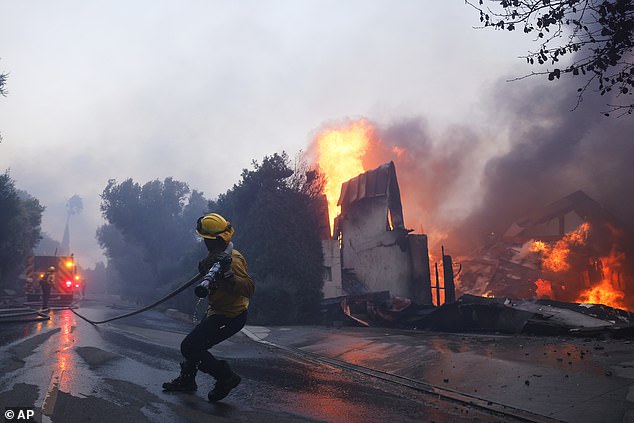 Fire crews battle the blaze as it burns structures in the Pacific Palisades area yesterday