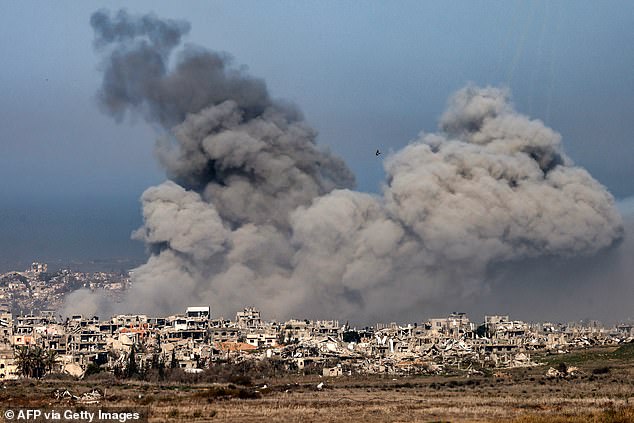 Smoke billows from explosions above destroyed buildings in the northern Gaza Strip on January 13