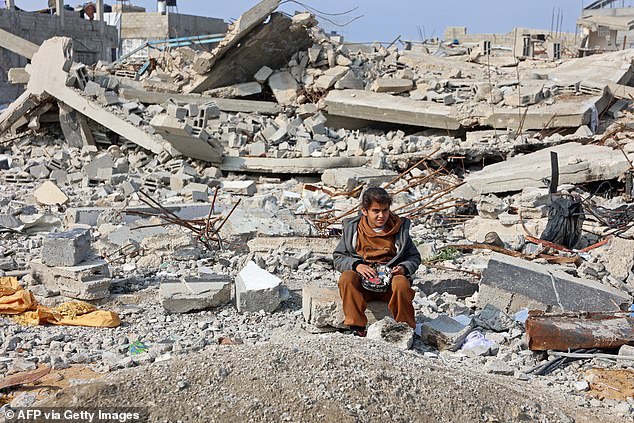 A Palestinian girl sits amid the rubble of buildings destroyed in Israeli airstrikes, in Gaza City on January 11