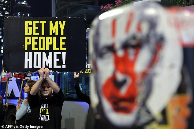 A demonstrator raises a placard during an protest calling for action to secure the release of Israelis held hostages, in front of the Israeli defence ministry in Tel Aviv on January 14, 2025